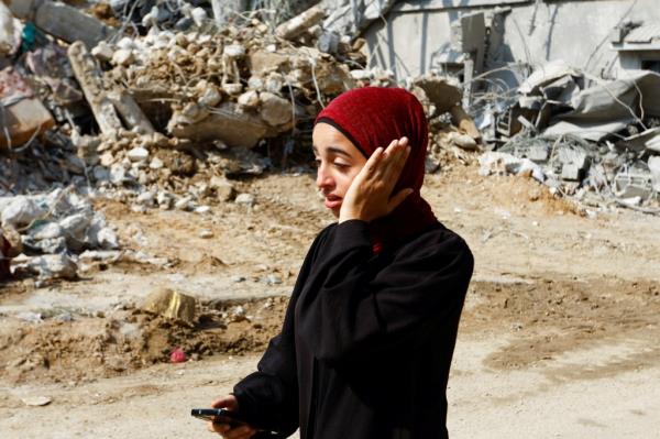 Palestinians are seen near an Israeli tank, near the fence of the Gaza-Israel border, east of the southern Gaza Strip city of Khan Younis, on Oct. 7, 2023.