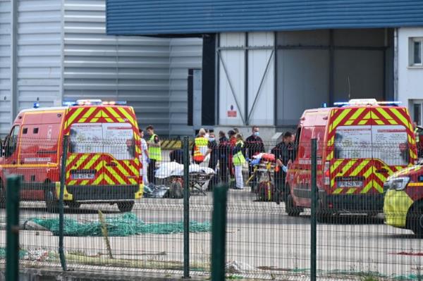 Firefighters handle the bodies of migrants who died trying to cross the English Channel